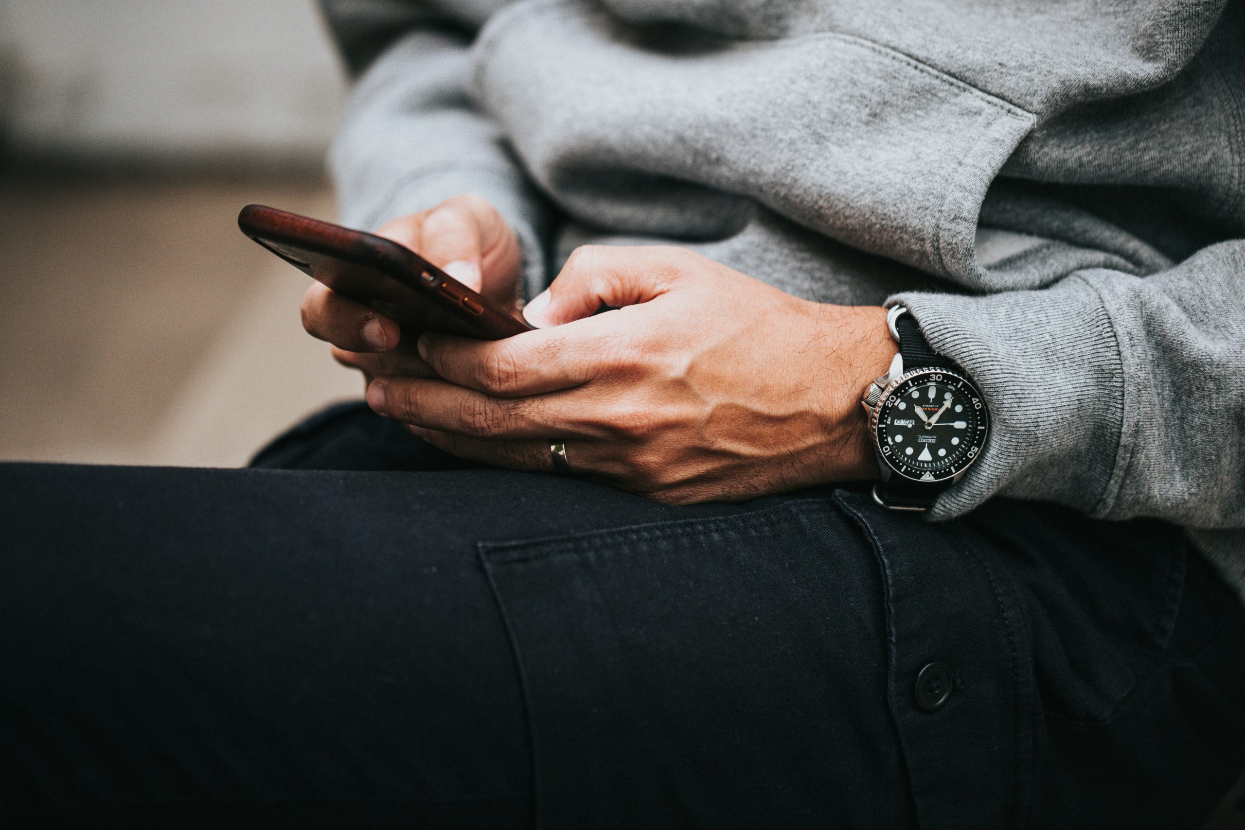 Close-up of a man's hands holding a mobile phone in his lap